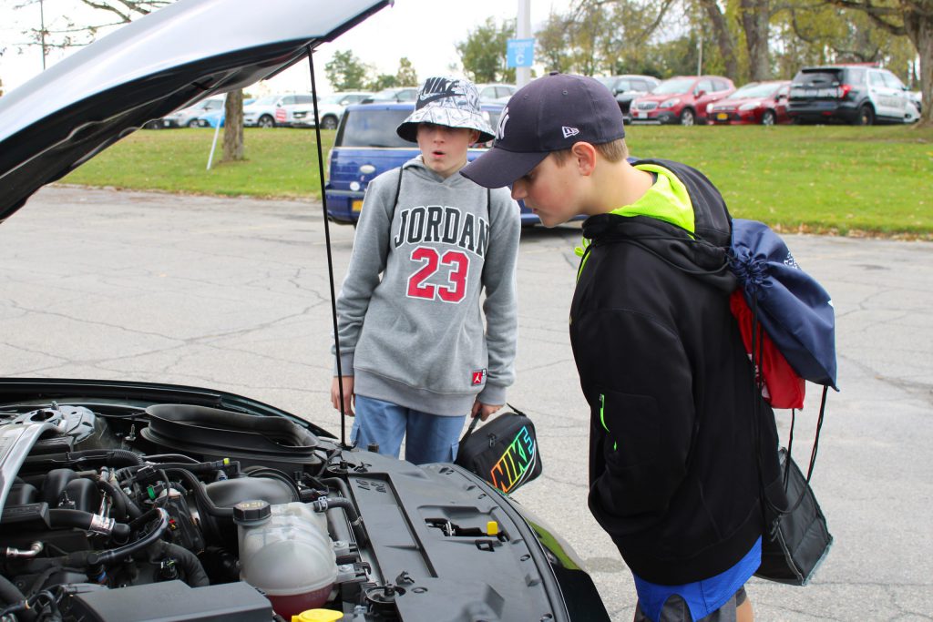 students looking inside car hood