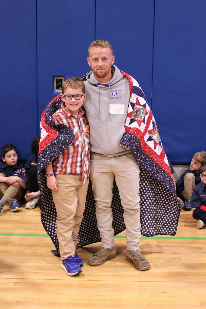 student and teacher embraced in a blanket