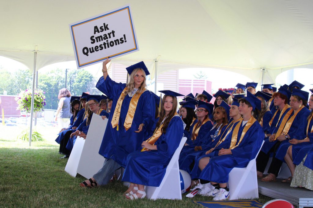photo of graduate class and one holding a sign