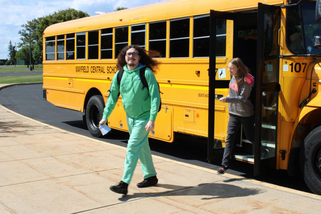 Person in green outfit walking out of bus.