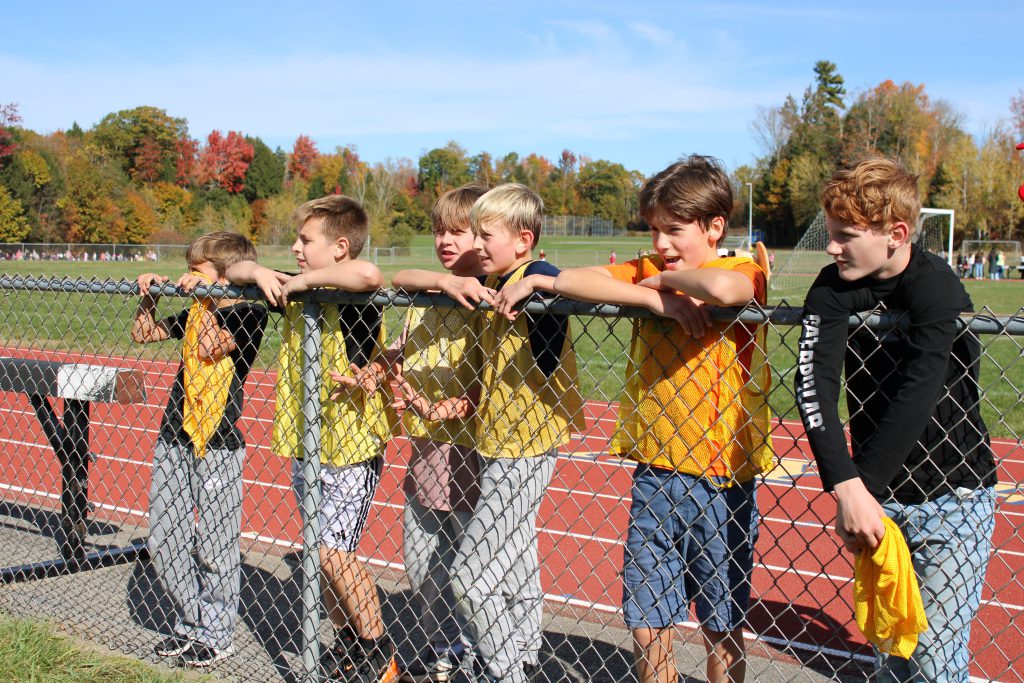 six students stand at the fence on running track