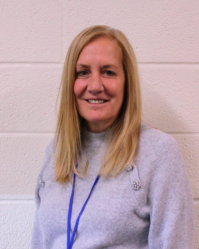 woman in sweater stands in front of a wall