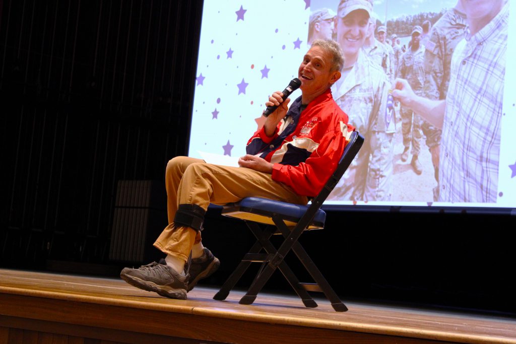 smiling man holds microphone and sits in chair