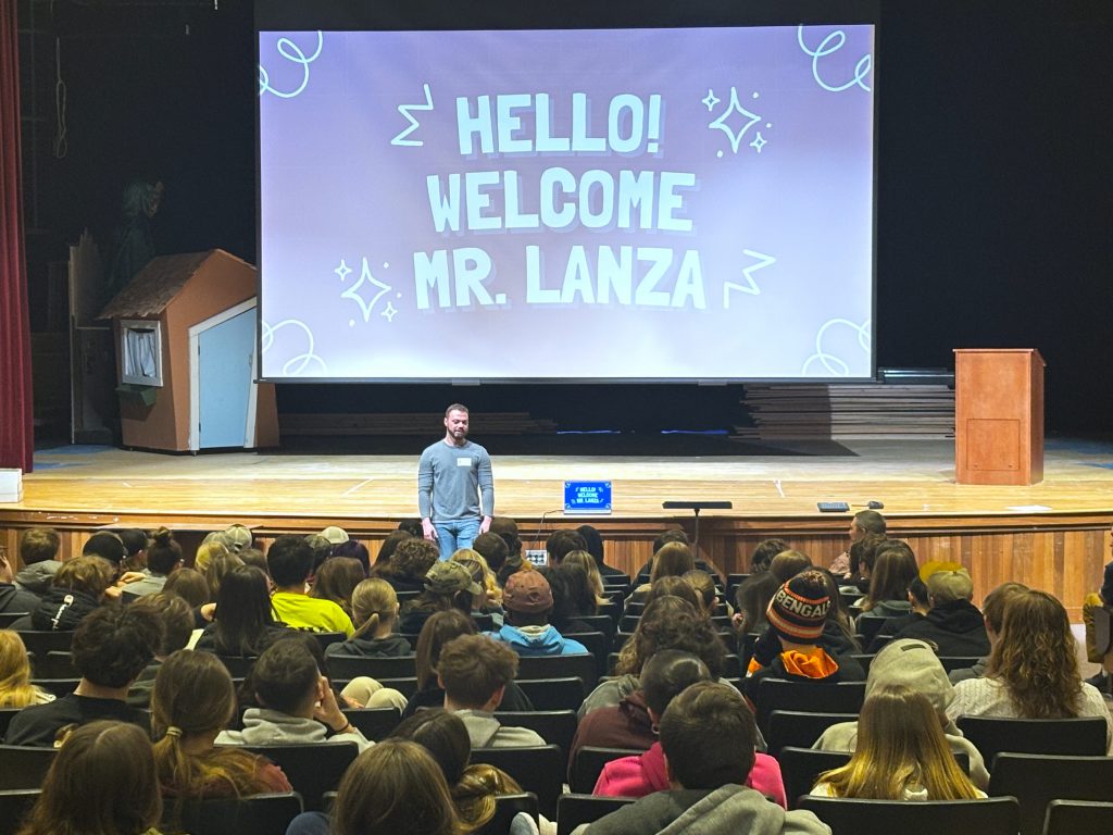 a man stands at the front of a auditorium of students