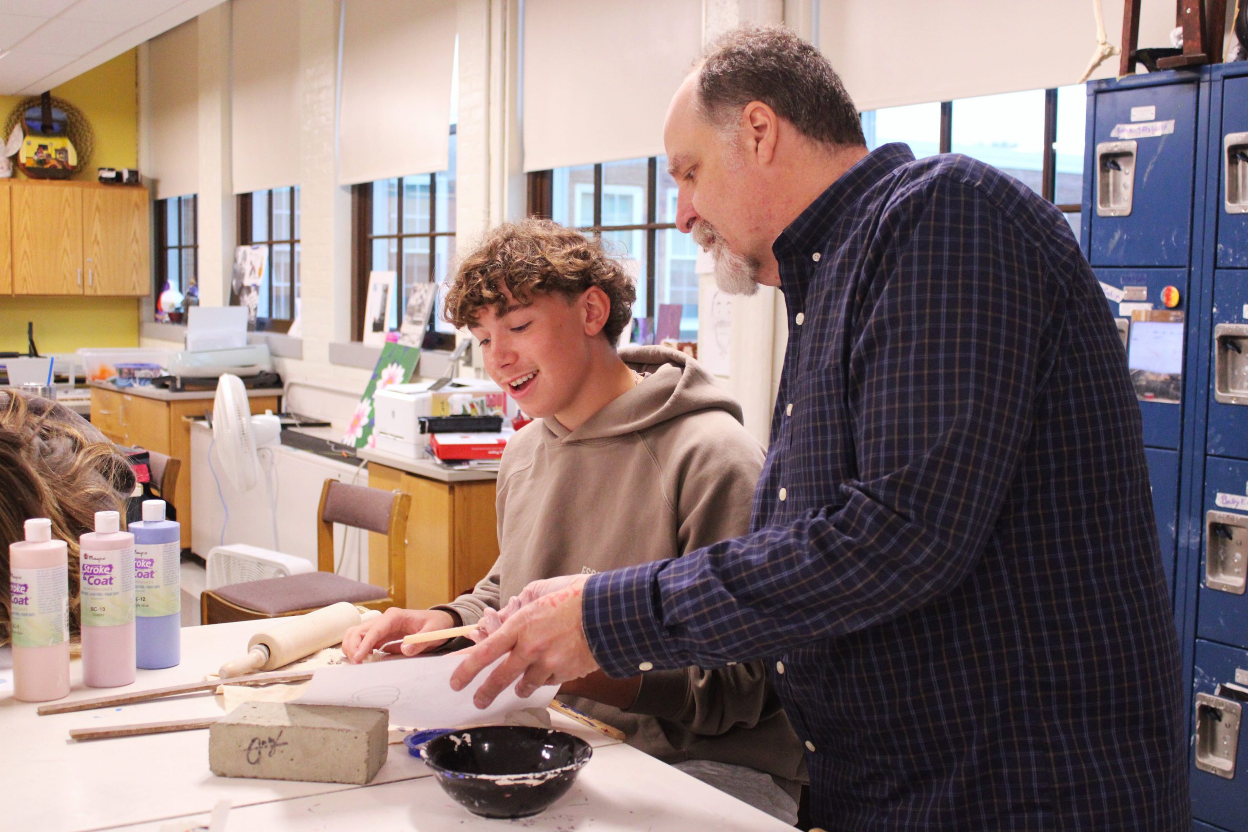 teacher shows student artwork in class