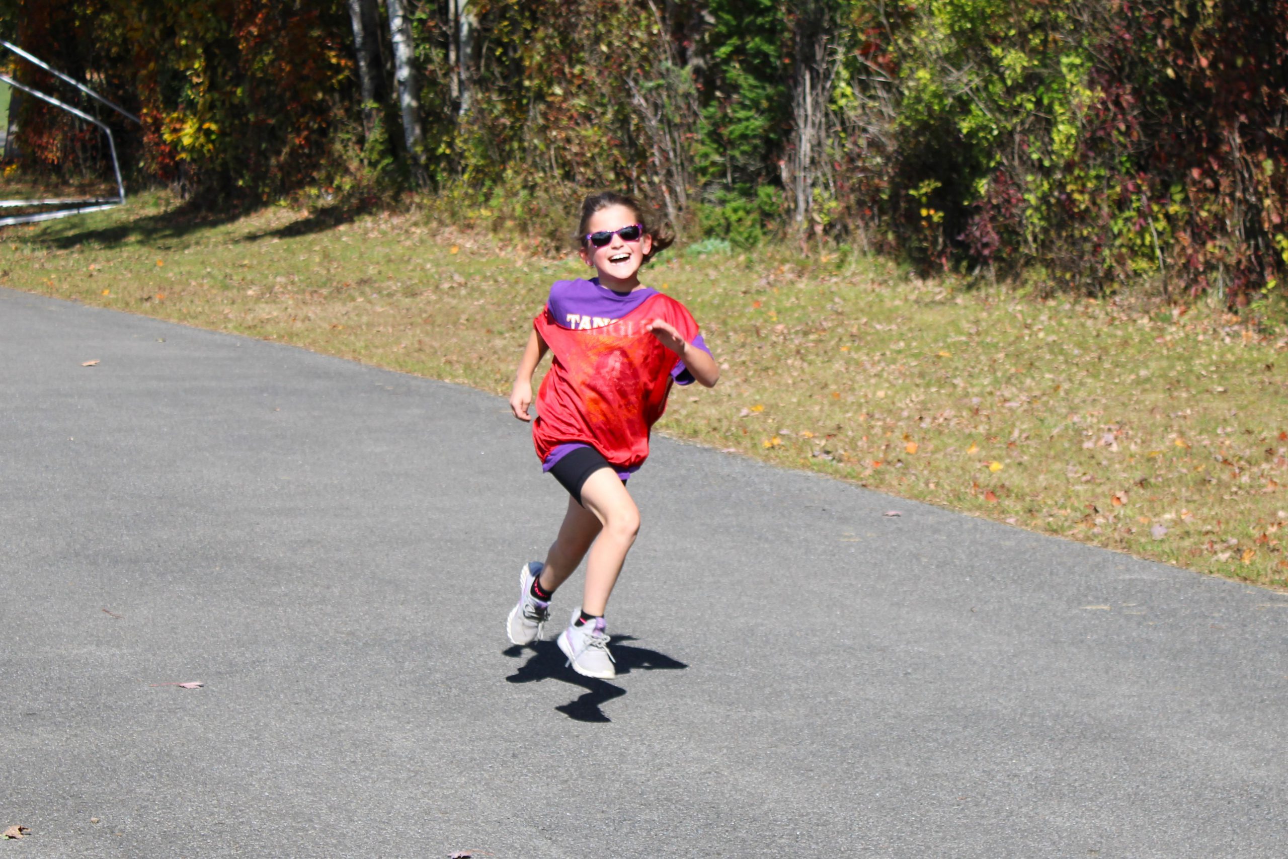 young girl wearing a red pinny runs and smiles